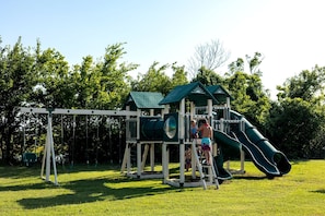 Un parque infantil con tobogán y columpios.
