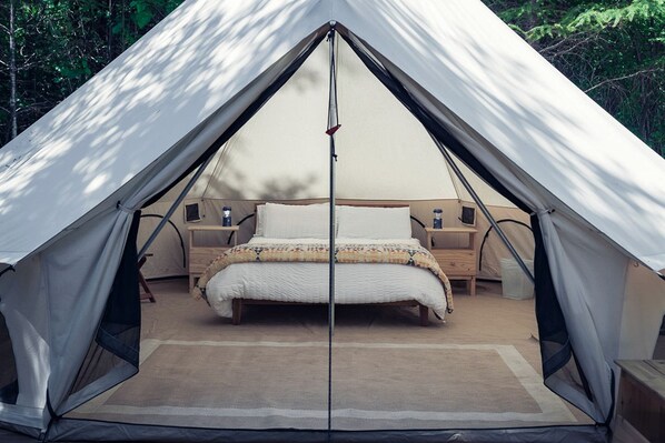 A tent with a bed, bedside tables, and a window. - Carson Glamping Escapes in this Wonderful Bell Tent Rental in Washington (Carson)