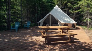 A tented accommodation with a picnic table and two chairs.