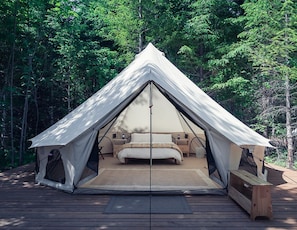 A tent with a bed, wooden deck, and forest background. - Carson Glamping Escapes in this Wonderful Bell Tent Rental in Washington (Carson)