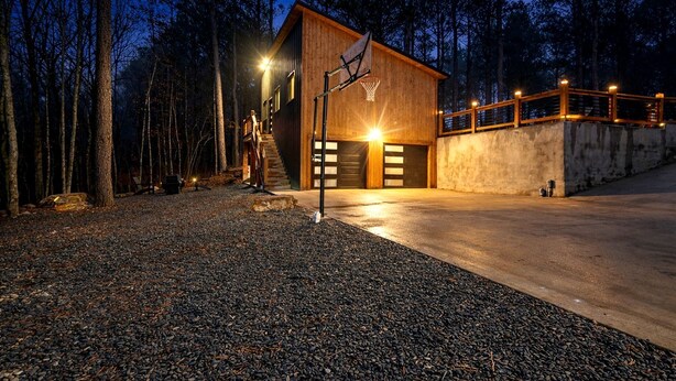 A modern wooden building with a basketball hoop, a staircase, and a concrete driveway. - Garage Loft • King + Bunks • Budget Friendly near Beavers Bend National Park (Broken Bow)