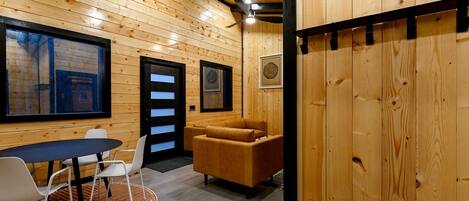 A wooden interior with a sofa, chairs, a table, and artwork on the walls.