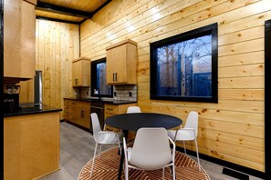 A wooden interior with a kitchen, dining area, and a large window. - Garage Loft • King + Bunks • Budget Friendly near Beavers Bend National Park (Broken Bow)
