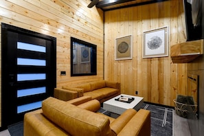 A wooden interior with a sofa, a coffee table, and framed artwork on the wall. - Garage Loft • King + Bunks • Budget Friendly near Beavers Bend National Park (Broken Bow)