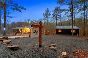 Een rustieke lodge met een bord waarop '75 Sturgeon Rd' en 'Dark Horse Loft' staat.