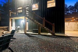 A modern building with a staircase, a covered outdoor area, and a gravel driveway. - Garage Loft • King + Bunks • Budget Friendly near Beavers Bend National Park (Broken Bow)