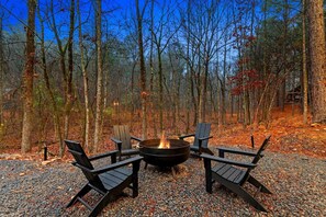 A fire pit with four Adirondack chairs in a forest setting. - Garage Loft • King + Bunks • Budget Friendly near Beavers Bend National Park (Broken Bow)