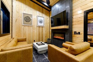 A wooden-paneled room with a fireplace, leather sofas, and framed artwork.