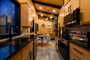 A modern kitchen with wooden cabinetry, a central island, and built-in appliances. - Garage Loft • King + Bunks • Budget Friendly near Beavers Bend National Park (Broken Bow)