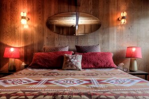 Une chambre à coucher avec une tête de lit en bois, deux lampes de chevet et une couvre-lit à motifs.