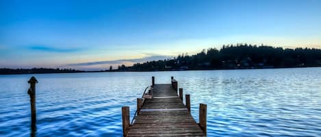 A wooden pier extending into calm water with a distant shoreline.
