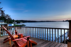 A wooden deck with a view of a calm lake and distant shoreline.