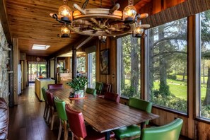 A wooden interior with a dining table, chairs, and a unique ceiling light fixture.