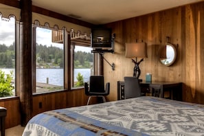 Una habitación con cama, escritorio, silla, televisor y vista al lago.