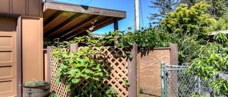 Un garaje residencial con puerta de madera, cerramiento de celosía y valla de malla metálica con plantas.