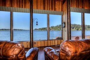 A cabin with large windows, leather seating, and a view of a lake.