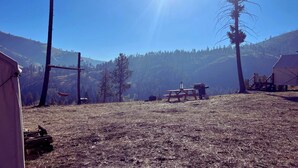 A campsite with tents, a picnic table, and a clear view of a forested mountain range.
