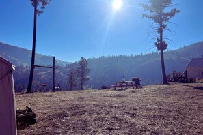 A campsite with tents, a picnic table, and a clear view of a forested mountain range.