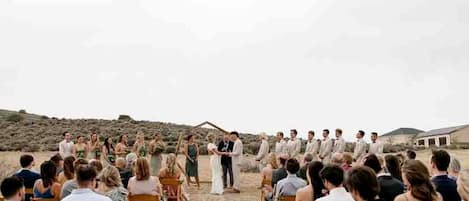 A wedding ceremony outdoors with guests seated in rows facing the couple.