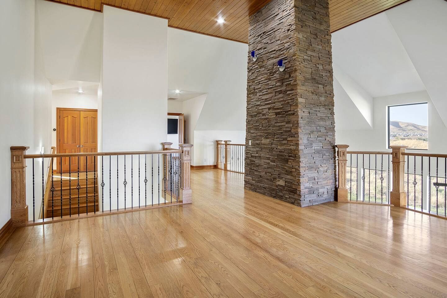 Un interior espacioso con un alto techo, una pared de acento de piedra y una escalera de madera.