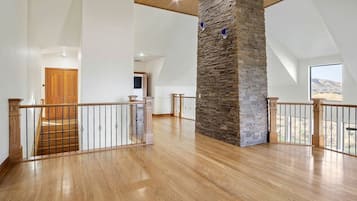Un interior espacioso con un alto techo, una pared de acento de piedra y una escalera de madera.