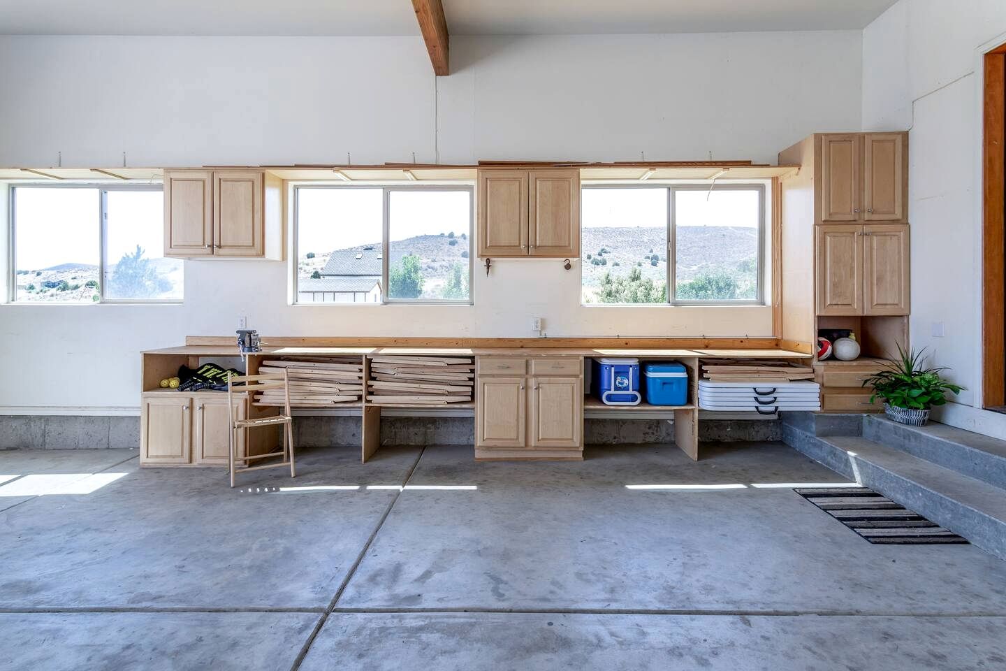 Une cuisine spacieuse dotée de grandes fenêtres, de meubles en bois et d’un plancher en béton.