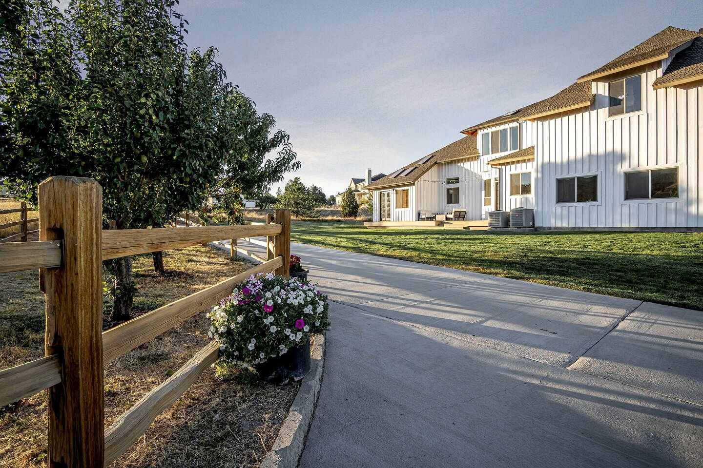 A residential street with houses, a wooden fence, and a flower bed.