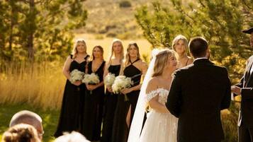 A wedding ceremony outdoors with a clear sky and a hilly landscape in the background.