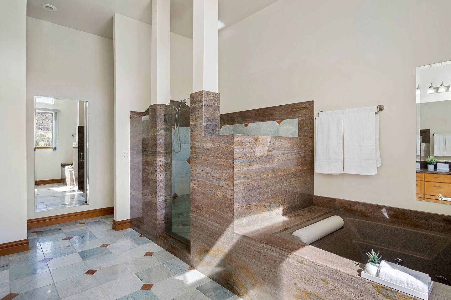 Une salle de bain moderne avec une douche à parois de verre, un sol carrelé en marbre et un grand miroir.