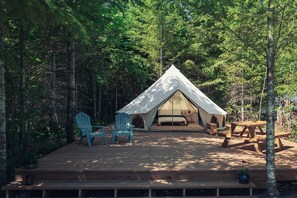 A tented accommodation with a deck, two chairs, and a table.