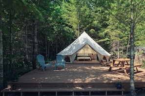 A tented accommodation with a deck, two chairs, and a table.
