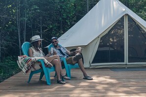 Two people sitting on turquoise chairs outside a tent on a wooden deck surrounded by trees. - Cute Bell Tent in Carson for Columbia Gorge Glamping in Washington (Carson)