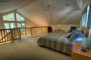 Un dormitorio con una cama grande, un escritorio, una silla, un ventanal y un balcón.