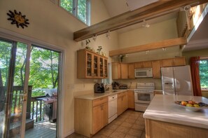 A kitchen with wooden cabinets, a microwave, an oven, and a sink. - Beautiful Cabin with Hot Tub Surrounded by Trees in Confluence, Pennsylvania (Confluence)