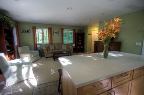 A spacious living room with a large sofa, a coffee table, and a dining area with a white island.