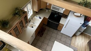 A kitchen with a microwave, stove, sink, and cabinets. - Beautiful Cabin with Hot Tub Surrounded by Trees in Confluence, Pennsylvania (Confluence)