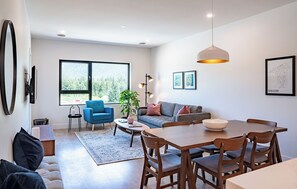 A modern living room with a sofa, blue armchair, dining table, and chairs.