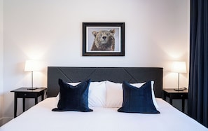 A hotel room with a large bed, two bedside tables, two lamps, and a framed artwork on the wall.