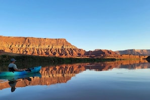 Un riu tranquil amb un kayakista, reflectint els penya-segats circumdants.