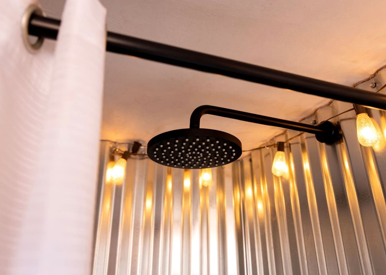 Ein Duschkopf mit schwarzem Griff und kreisförmigem Design, an einer schwarzen Metallstange befestigt.