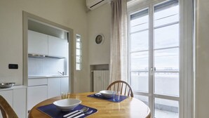 A dining area with a round wooden table, chairs, and a view of the outside through a large window.