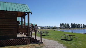 A wooden cabin with a porch, outdoor seating, and a view of a lake. - Fantastic Cabin with Fire Pit Close to West Yellowstone, Montana (West Yellowstone)