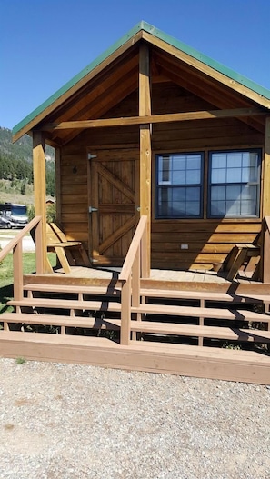 A wooden cabin with a green roof, a large window, and a door. - Fantastic Cabin with Fire Pit Close to West Yellowstone, Montana (West Yellowstone)