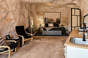 Een slaapkamer met een bed, nachtkastjes, een stoel, een spiegel en een wastafel.