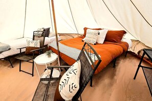 A tent with a bed, two chairs, a small table, and a hanging light. - Stunning Family Glamping Tent for a True Outdoor Experience on a Secluded Ranch in Moab, Utah (Moab)
