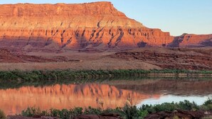 A natural landscape with a river reflecting a mountain range.