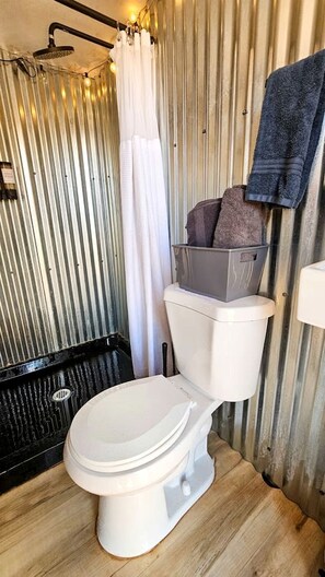 A compact bathroom with a toilet, shower, and a towel rack. - Stunning Family Glamping Tent for a True Outdoor Experience on a Secluded Ranch in Moab, Utah (Moab)