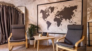 A room with two wooden chairs, a small table, a potted plant, a world map on the wall, and a curtain. - Beautiful Cave by the Colorado River with Stunning Canyon Views for a Unique Adventure in Moab, Utah (Moab)