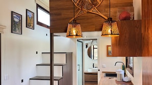 Eine moderne Küche mit einer Holz Arbeitsplatte, zwei Korbstühlen und einer Treppe zu einem anderen Raum.