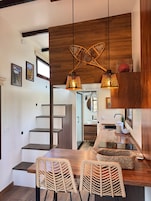Una cocina moderna con una encimera de madera, dos sillas de mimbre y una escalera que lleva a otra habitación.